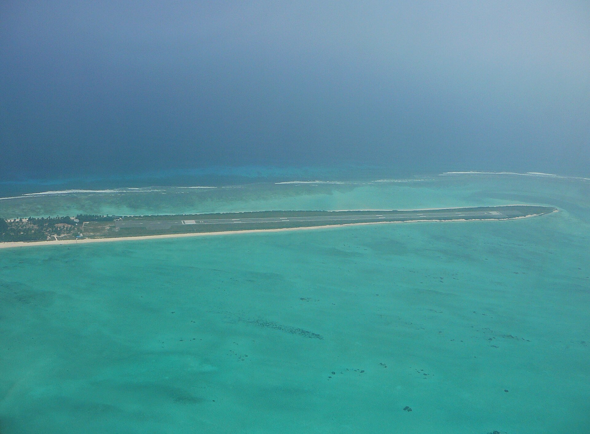 Aerial view of the spectacular narrow airstrip runway on Agatti Island surrounded by glowing turquoise coral lagoon waters in Lakshadweep