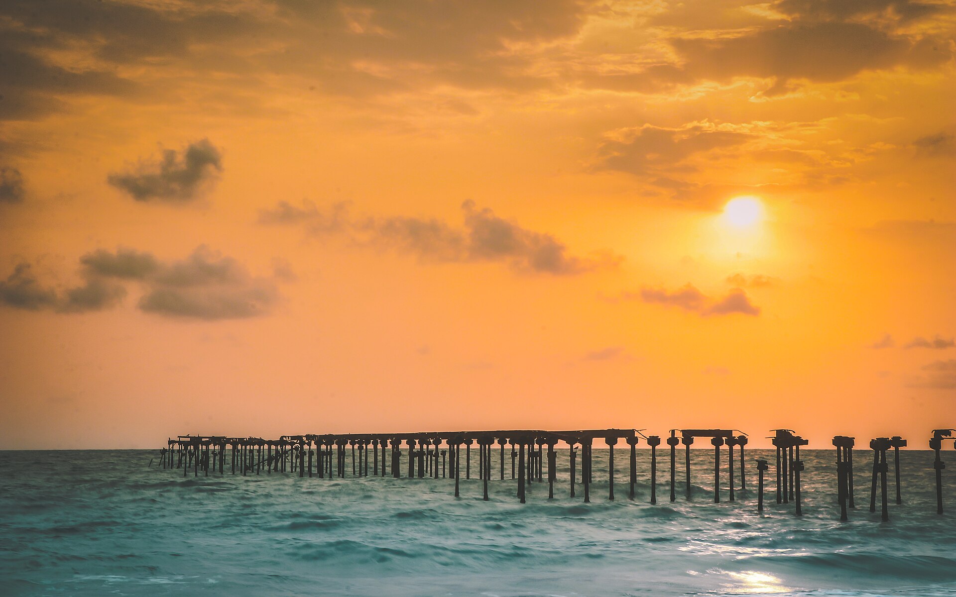 Atmospheric skeletal wooden and iron ruins of the 1862 Hugh Crawford sea pier standing in the surf at Alappuzha Beach in Kerala