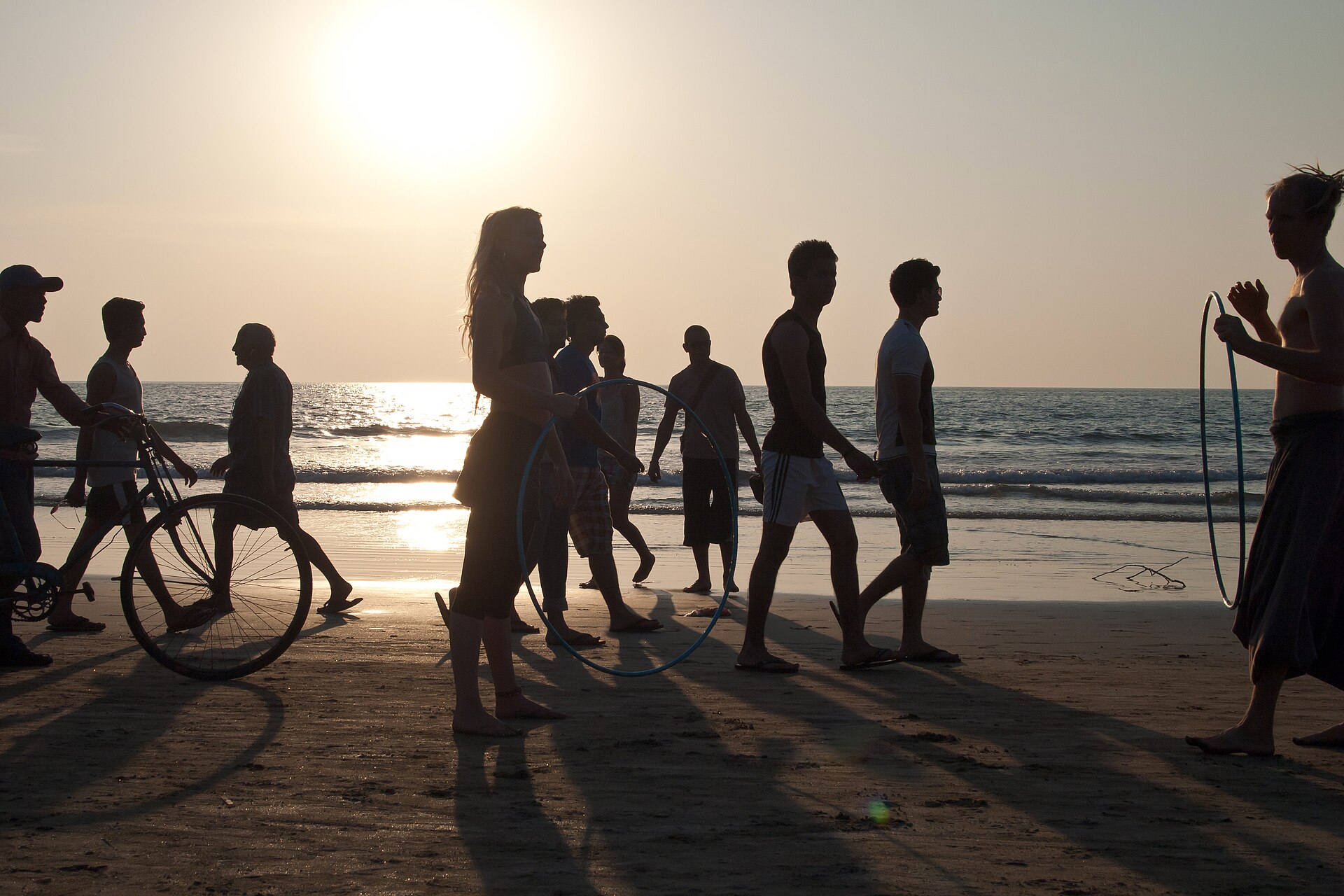 Vibrant golden sunset crowd and gathering along the curving sandy shoreline of Arambol Beach in North Goa