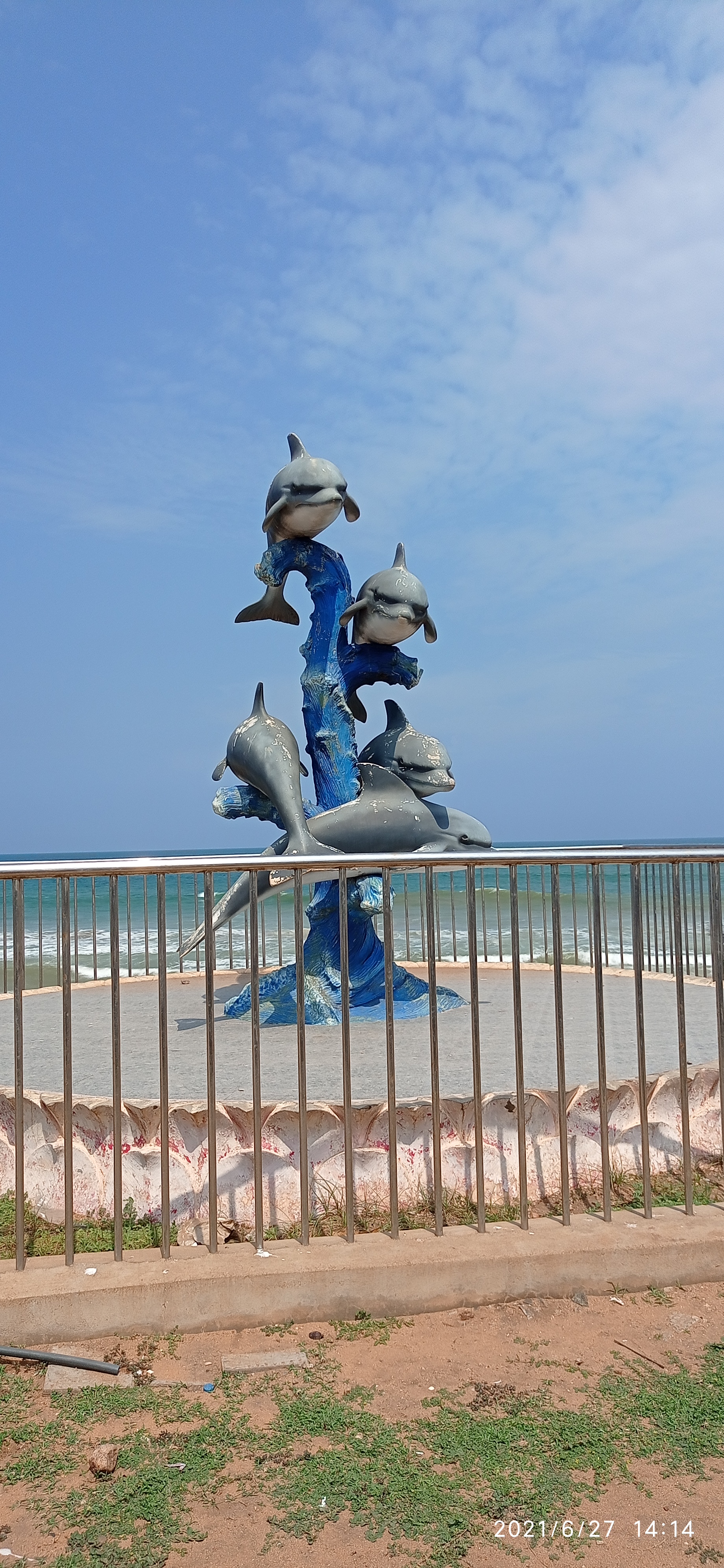 Seaside dolphin statues, broad golden sandy shoreline, and blue Bay of Bengal at Bheemunipatnam Beach in Visakhapatnam