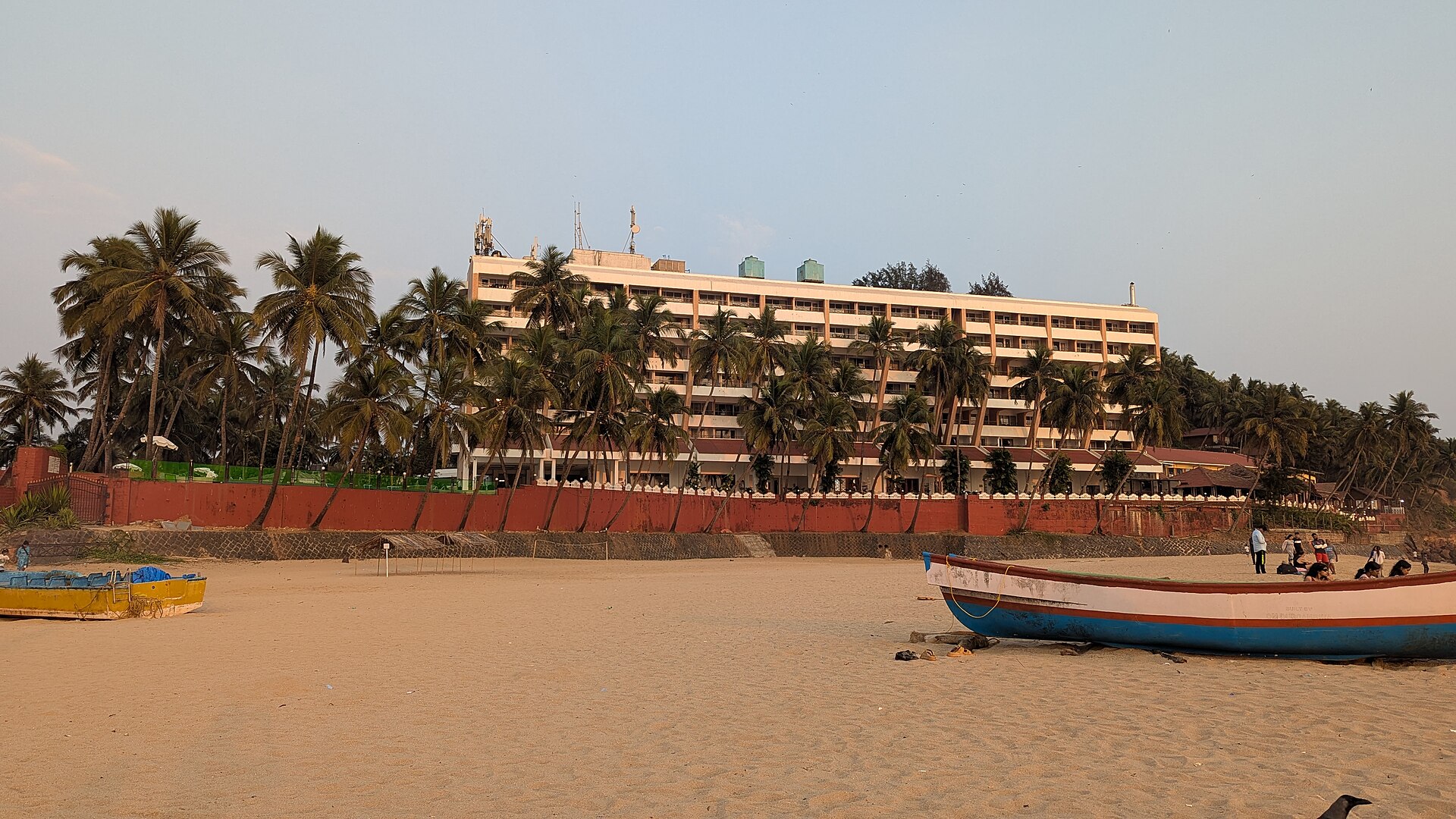 Sheltered curving crescent sandy bay, beachfront resort, and Arabian Sea waves at Bogmalo Beach in South Goa