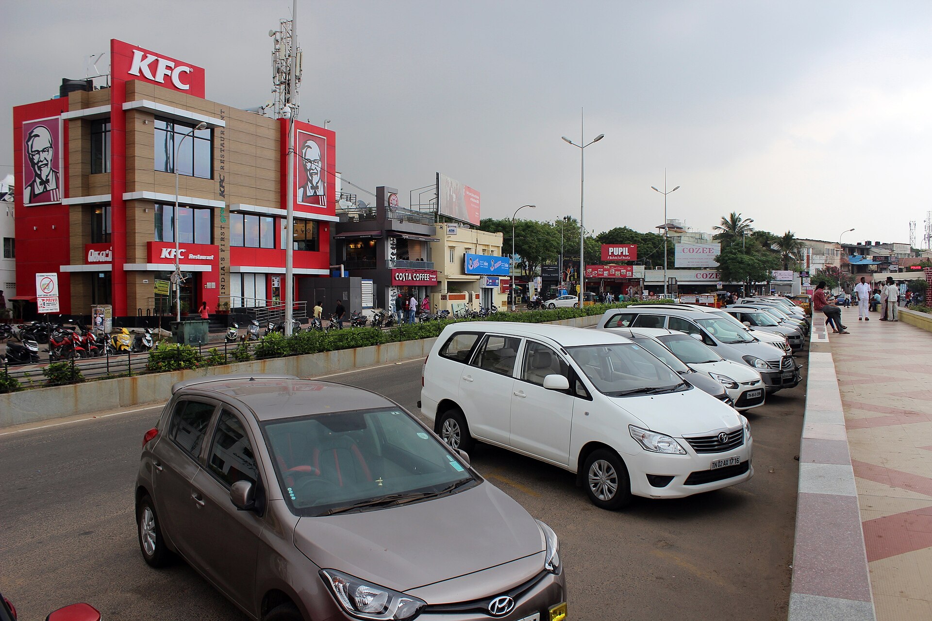 Broad golden sandy beach, paved pedestrian promenade road, and open Bay of Bengal waters at Elliot's Beach in Besant Nagar Chennai