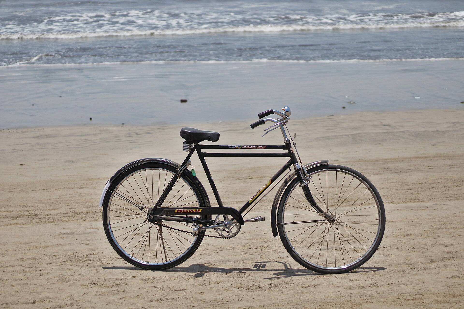 Expansive golden sandy shore, morning cyclists, and crashing waves of the Arabian Sea at Juhu Beach in Mumbai
