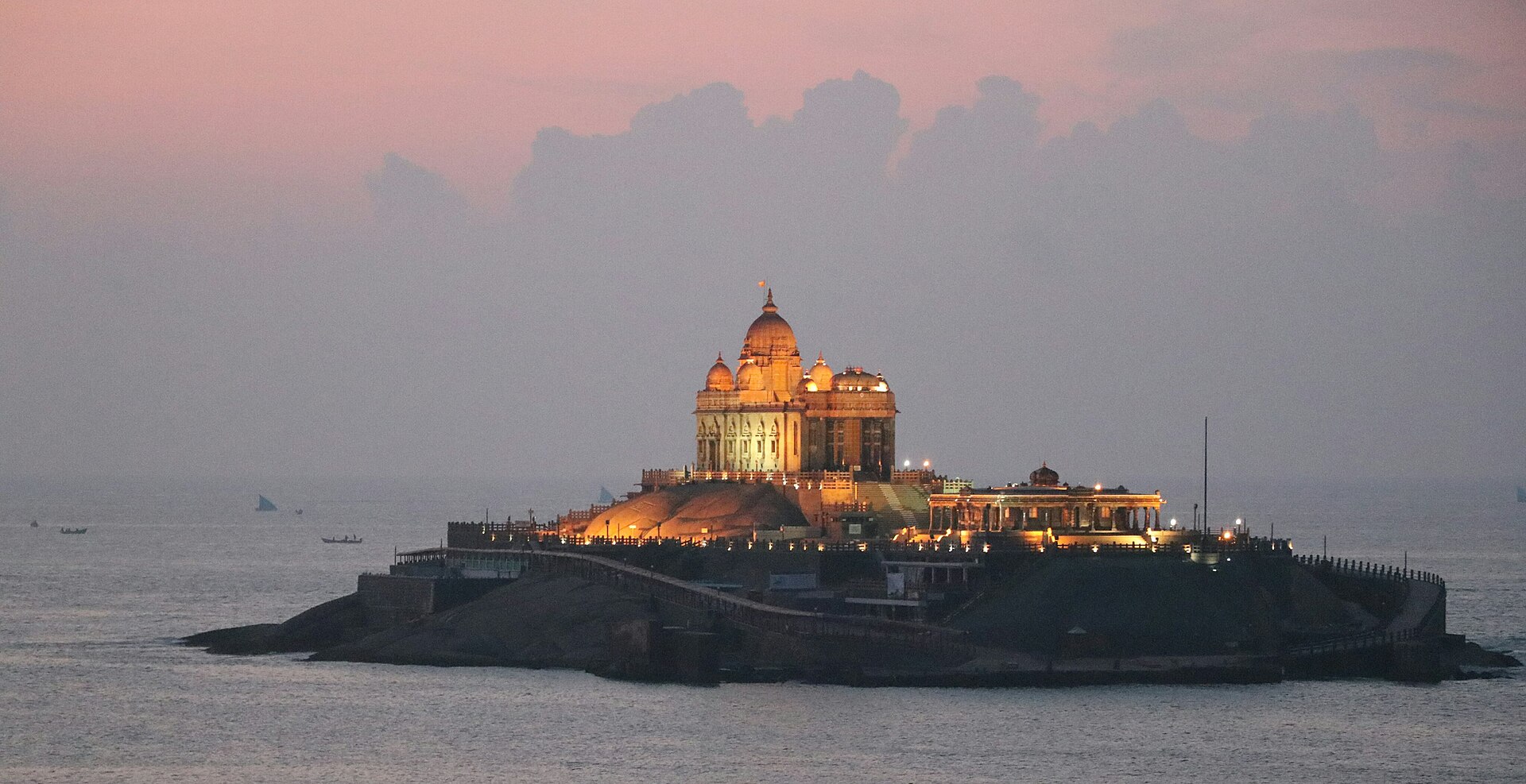 Iconic Vivekananda Rock Memorial standing atop granite island rocks in the crashing triple-ocean surf at Kanyakumari in Tamil Nadu