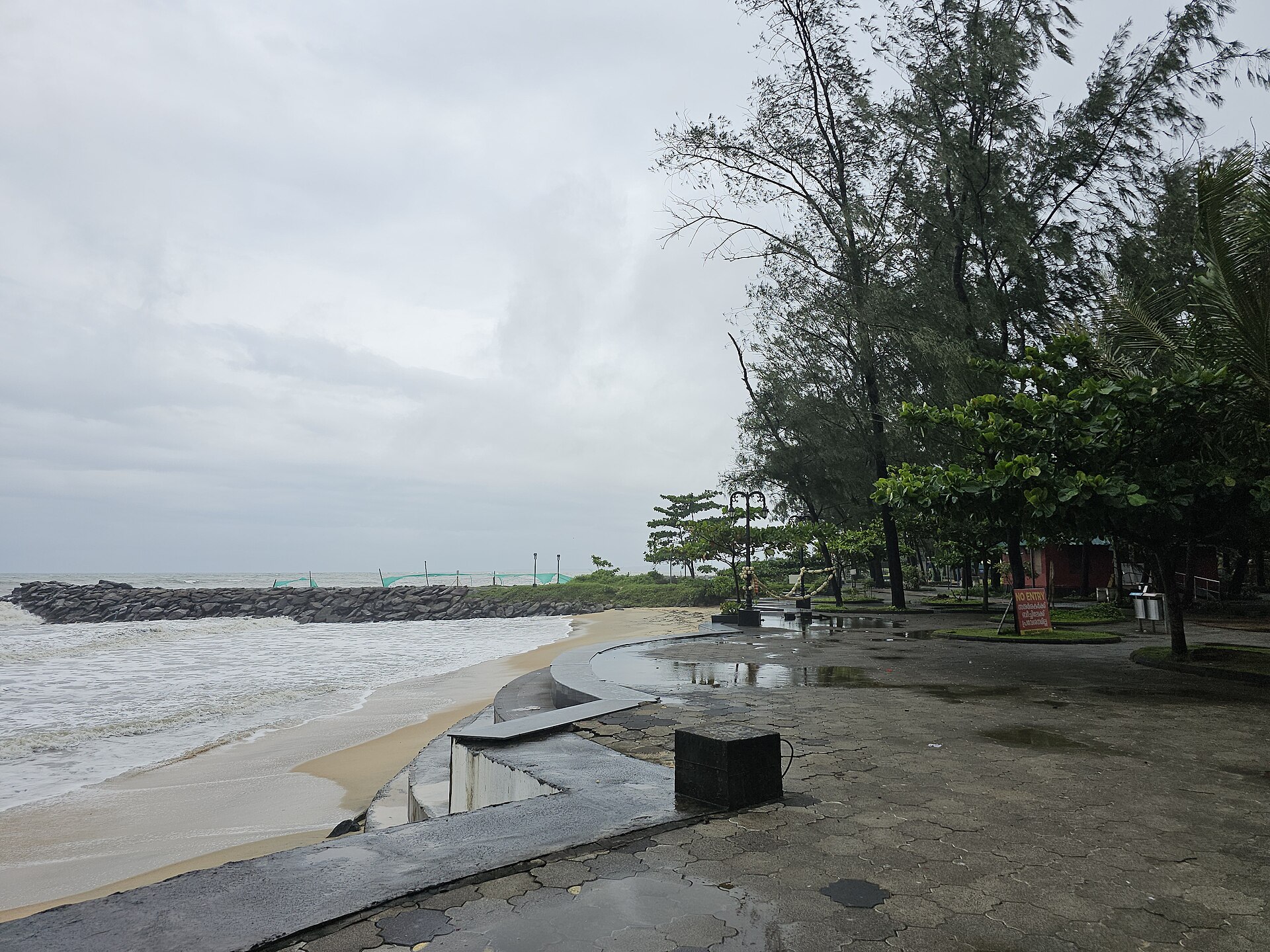 Rocky headland, golden sand shoreline, and breaking Arabian Sea waves at Kappad Beach in Kozhikode, Kerala