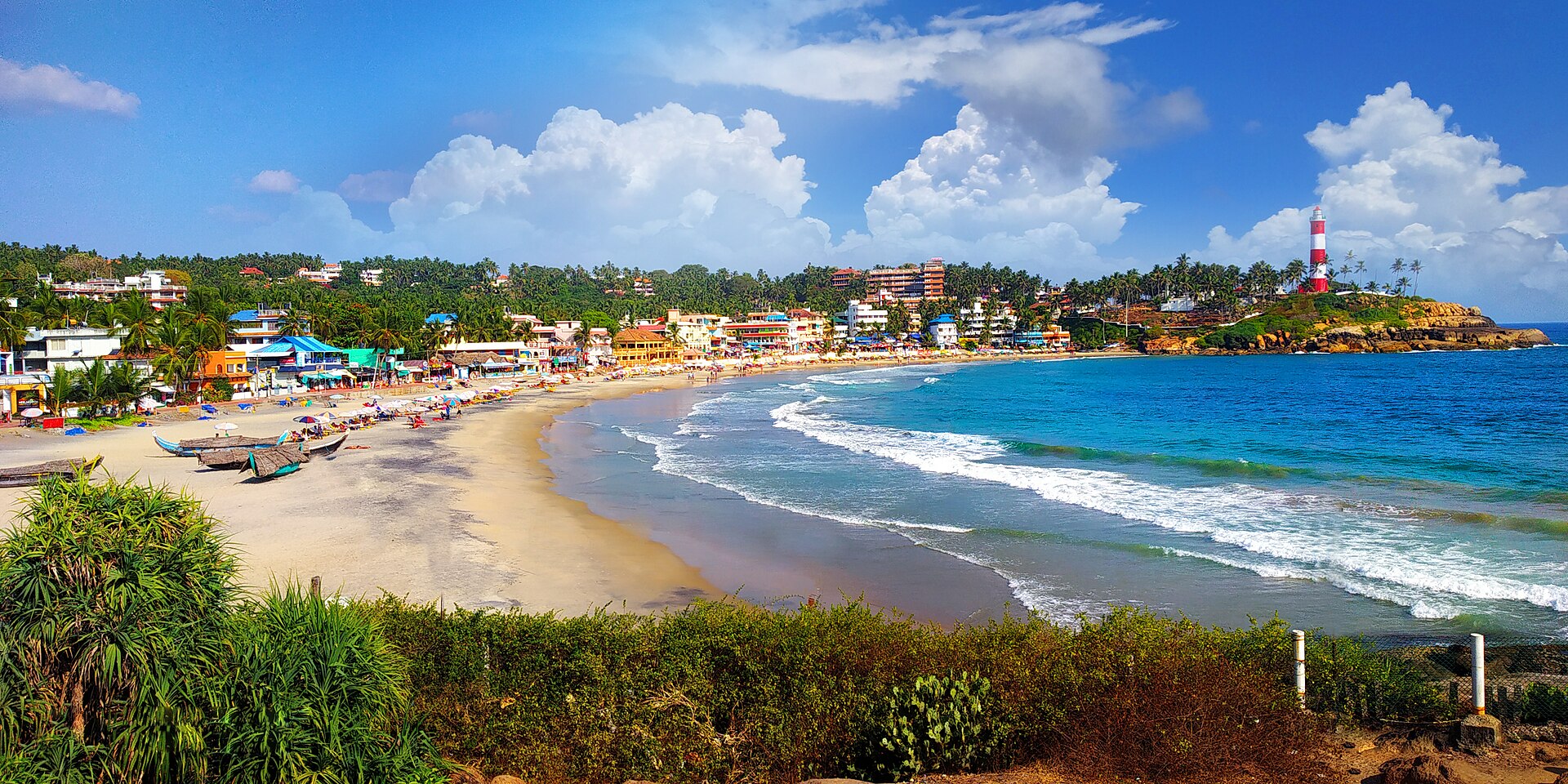 Iconic red and white striped Vizhinjam Lighthouse on rocky promontory overlooking Kovalam Lighthouse Beach in Kerala