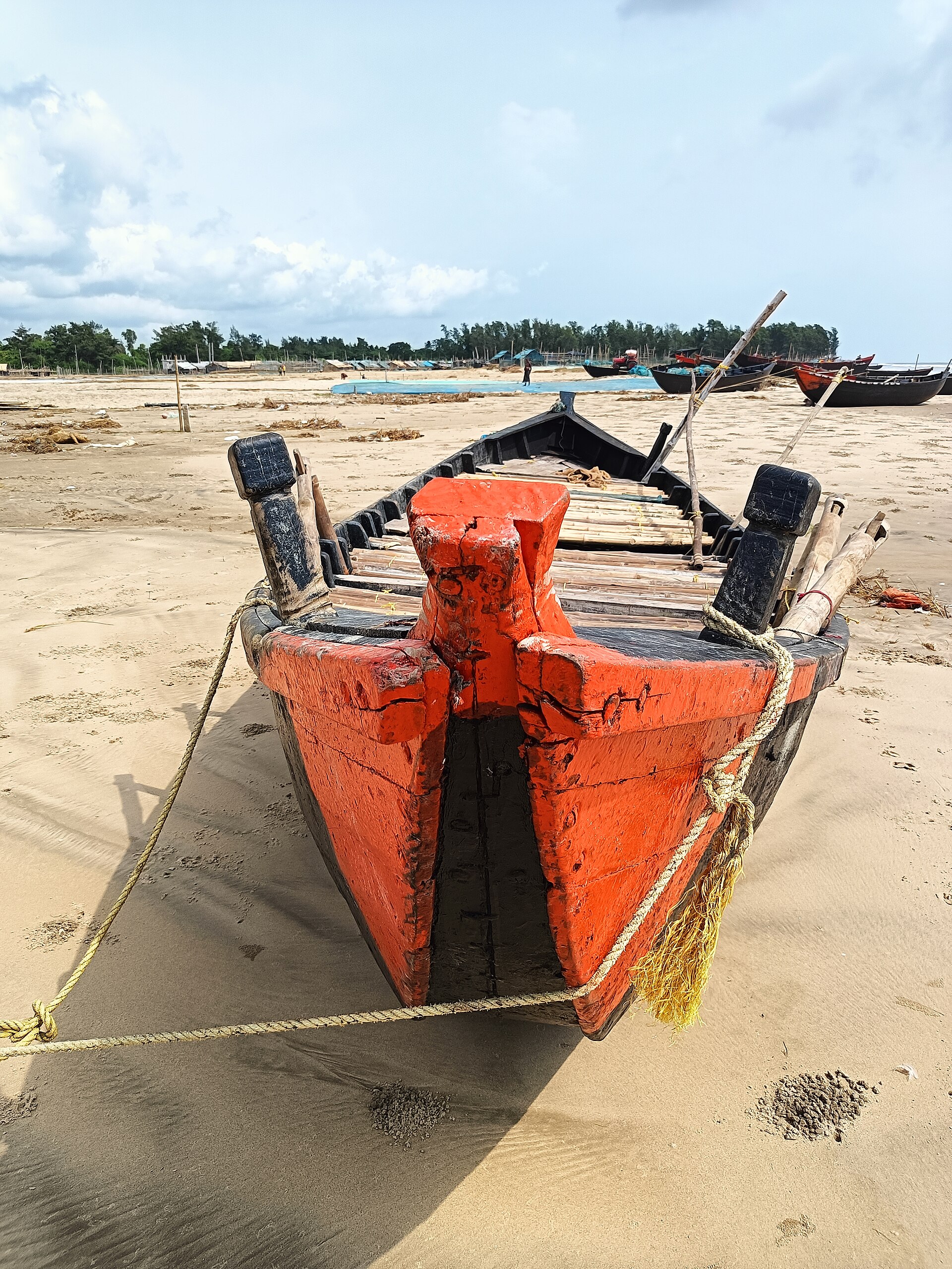 Vast expansive hardpacked wet sand foreshore and wooden fishing boat on Mandarmani Beach in Purba Medinipur, West Bengal