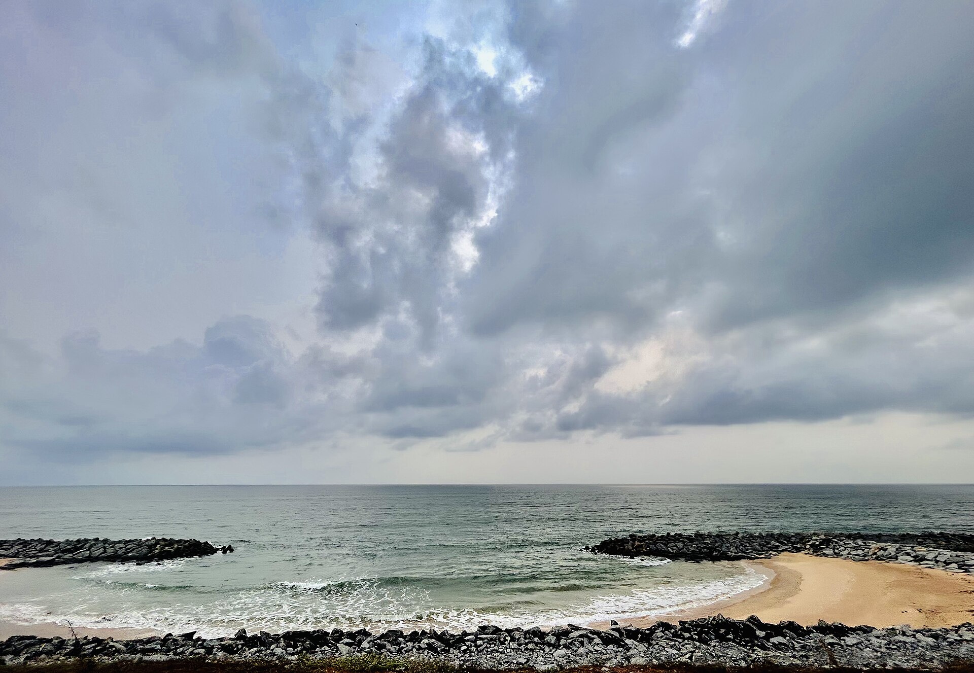 Scenic highway NH66 running between the Arabian Sea waves and the placid Souparnika River at Maravanthe Beach in Karnataka
