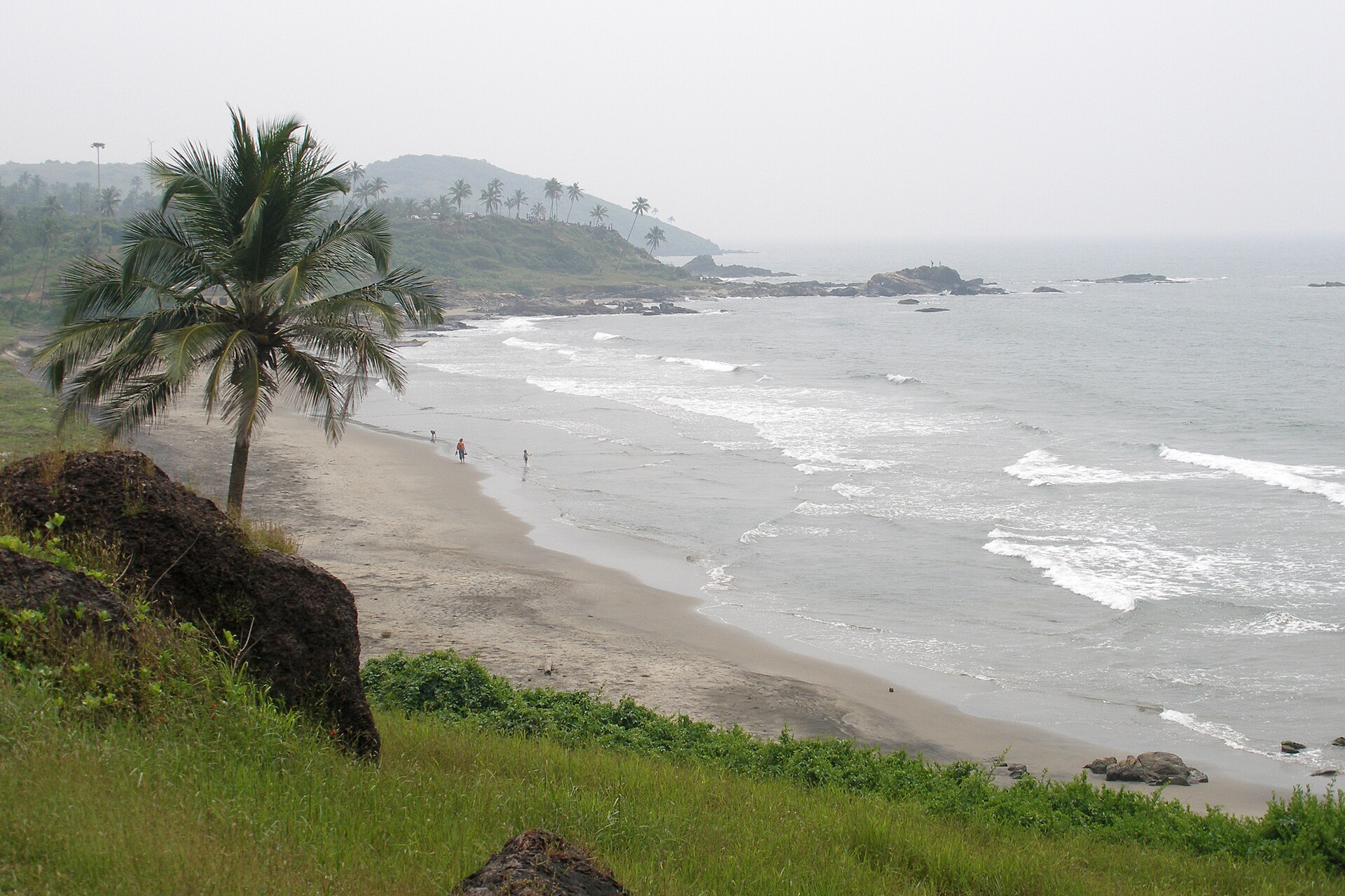 Curving golden bay, red laterite cliffs, and blue Arabian Sea at Vagator Beach in North Goa